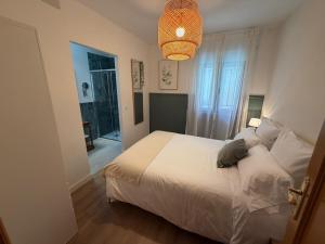 a bedroom with a white bed and a chandelier at Cereza Home in Cabezuela del Valle