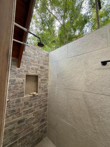 a bathroom with a stone wall and a shower at Sierra Jungla in Minca