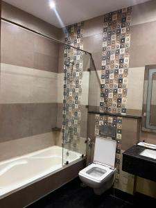 a bathroom with a toilet and a tub and a sink at HotelMaple Ridge in Tājganj