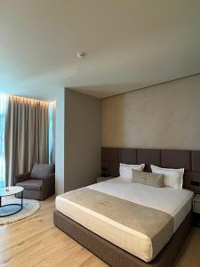 a bedroom with a large bed and a chair at South Inn Hotel in Vlorë