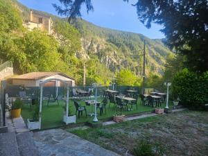 a garden with tables and chairs with a mountain in the background at Auberge Du Riou in Puget-Rostang
