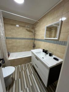a bathroom with a sink and a tub and a toilet at Apartament Uricani in Uricani