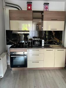 a kitchen with white cabinets and a black oven at Apartament White Tower in Ploieşti
