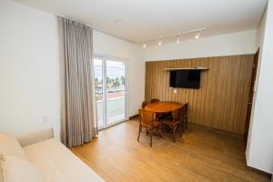 a living room with a dining room table and a television at Landruá Flat in São Luís