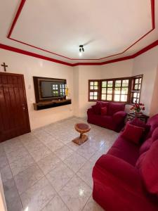 a living room with red couches and a tv at Casa de Temporada Ipê Rosa in Bonito