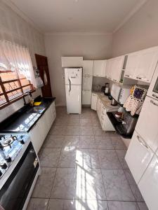 a kitchen with white cabinets and a white refrigerator at Casa de Temporada Ipê Rosa in Bonito