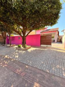 a tree in front of a pink wall with a bench at Casa de Temporada Ipê Rosa in Bonito