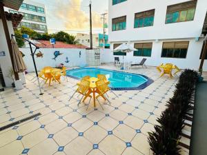 a patio with yellow tables and chairs and a pool at Pousada Sal e Mar Maracaipe in Porto De Galinhas