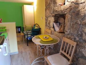 a table and chairs in a room with a stone wall at Calypso's Cave the Apartment for Animal Lovers in Babino Polje