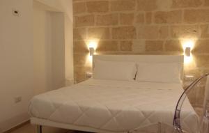 een wit bed in een kamer met een bakstenen muur bij Lamia Room Rentals in Matera