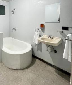 a white bathroom with a tub and a sink at Zenora Suites in San José
