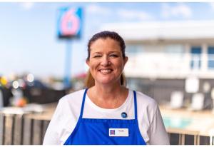 a woman in a blue apron smiles at the camera at Studio 6 Spindale, NC Forest City in Spindale