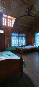 a bedroom with two beds and two windows at Saamiyanaa Cloud Nest in Kalimpong