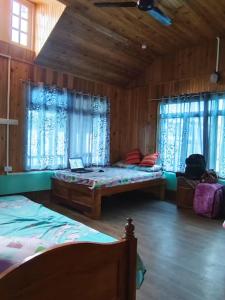 a bedroom with two beds in a room with wooden walls at Saamiyanaa Cloud Nest in Kalimpong