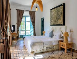 a bedroom with a white bed and a large window at Villa Marrakech Beldi in Najem