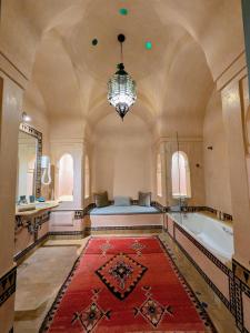 a large bathroom with a tub and a bed and a chandelier at Villa Marrakech Beldi in Najem