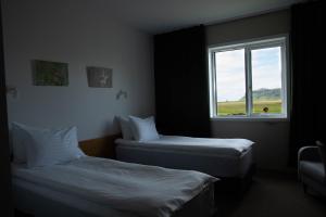 two beds in a room with a window at Hótel Búrfell in Vík