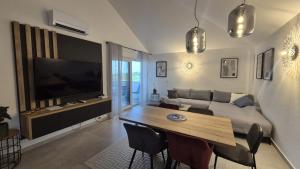 a living room with a couch and a table with chairs at Rimac Apartments in Novalja