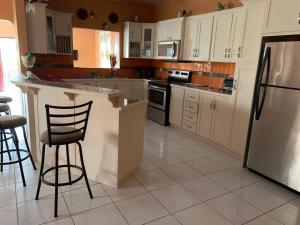 a kitchen with white cabinets and a counter with stools at Alluring Ambrosia in Arouca
