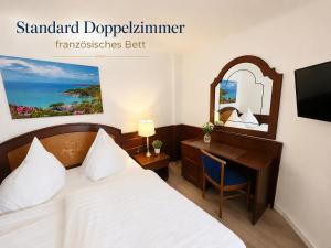 a hotel room with a bed and a desk and a mirror at Hotel Garni Italia in Bühl +3 photos