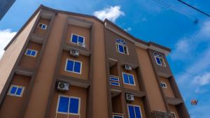 a brown building with blue windows on it at Hotel Mandelson in Godomey