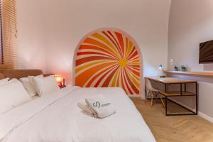 a bedroom with a large white bed with a colorful wheel on the wall at DAR MEMOIR Apart Hotel in Al Mudawwar
