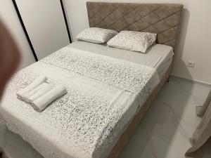 a bed with white sheets and pillows on it at Apartments Aroma in Tomba
