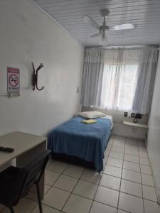 a small bedroom with a bed and a window at Eduardos Hotel in Rio do Sul