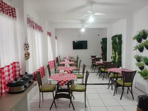 a dining room with tables and chairs and a tv at Eduardos Hotel in Rio do Sul