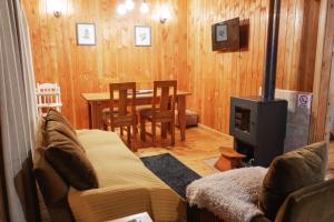 a living room with a couch and a table with a fireplace at Cabañas en neltume in Neltume