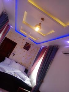 a bedroom with a bed and a ceiling with blue lights at Hotel Mandelson in Godomey +2 photos