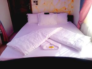a bed with white sheets and two towels on it at Hotel Mandelson in Godomey