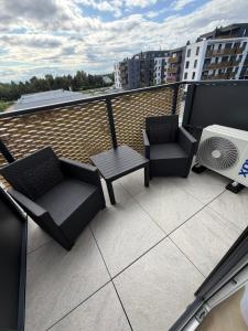 a balcony with two chairs and a table and a fan at Apartament Kaszmirowy in Nysa