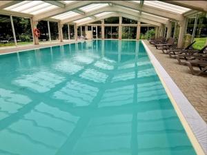 a large swimming pool with blue water at Terracotta Lodge - Un cocon chaleureux pour des vacances inoubliables in Nibelle