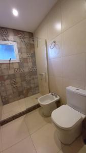 a white bathroom with a toilet and a shower at Brisas Apart in Olavarría