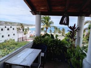 a table on a balcony with a view of the beach at MayFlower Hotel & Hostal in Puerto Escondido