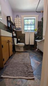 a bathroom with a toilet and a shelf with towels at Live Oak Home with Garden Studio in Gainesville