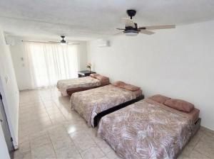 a bedroom with two beds and a ceiling fan at Casa San Pedro in Mérida