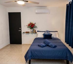 a bedroom with a bed with blue sheets and a ceiling fan at Casa San Pedro in Mérida