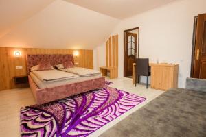 a bedroom with a large bed and a purple rug at Casa Leda in Sovata