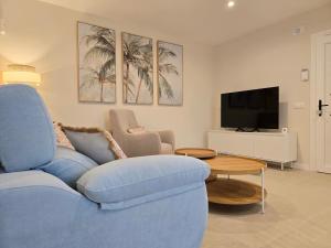 a living room with a blue couch and a tv at LURDE Apartamentos Rurales in El Cerezal