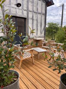 a wooden deck with a bench and a table at Cottage de charme avec piscine et vue panoramique - 6-8 pers Pays d'Auge in Vimoutiers