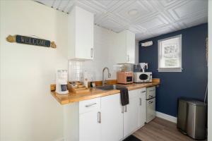 a kitchen with white cabinets and blue walls and a sink at The Beachside Co in Sylvan Beach