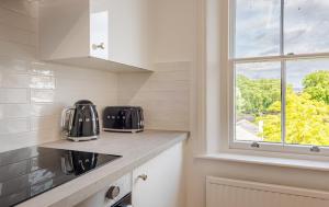 a kitchen with white cabinets and a window at Chic 1BR Teddington Apartment Modern & Bright in Kingston upon Thames