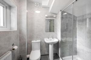 a bathroom with a toilet and a sink and a shower at Elegant 2BR Ground-Floor Teddington Flat Modern Comfort in Kingston upon Thames +25 photos