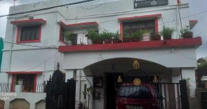 a white building with red windows and potted plants at THUBE Saheb B&B in Jabalpur