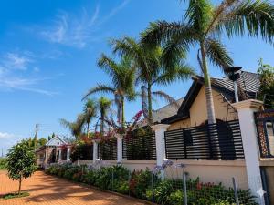 a house with palm trees and a fence at Paradise Creek Hotel in Tamale