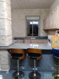 a kitchen with a counter with two bar stools at بيت مريم in Irjān