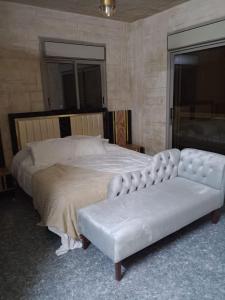 a bedroom with a large bed with a white couch at بيت مريم in Irjān