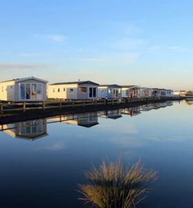 a row of houses on a dock next to the water at Maisy's Retreat in Chapel Saint Leonards